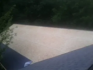 New OSB roof sheathing installed beside an existing shingle roof in Chariton