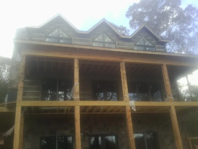 Dormers and porch framing on a large log home under construction — Roof Coating work by our crew in Chariton